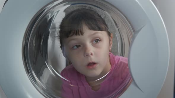 Child Look To a Washing Machine. alt
