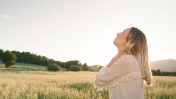 Woman standing on farm field and looking up to the sky during sunset,close up