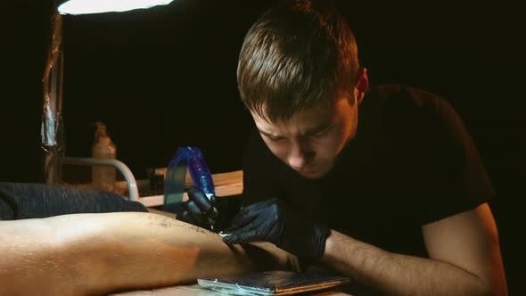 Tattoo Artist Work on Customer Leg Under Lamp Light in Dark Room