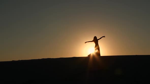 Girl Cute Performs Beautiful Belly Dance on Sunset Background. Silhouette alt