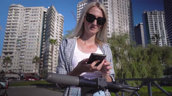 Woman unlocks electric scooter app with her smartphone. alt