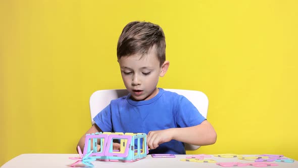 Clever boy playing with colored children's designer. alt