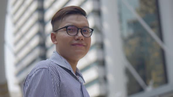 Portrait Asian businessman smiling and looking at camera standing on the urban city.