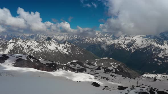 Air Flight Through Mountain Clouds Over Beautiful Snowcapped Peaks of Mountains and Glaciers alt