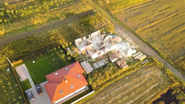 Top down aerial view of two private houses, one under construction with wooden roofing frame  alt