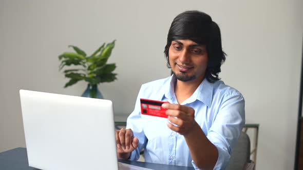 Young Indian Man with Credit Card in Hands Making Purchases Online