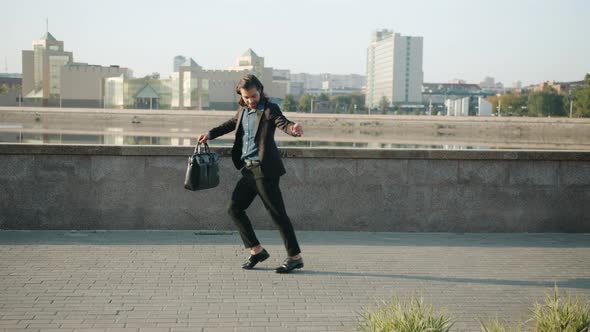 Creative Businessman Dancing at River Embankment Moving and Having Fun on Sunny Day alt