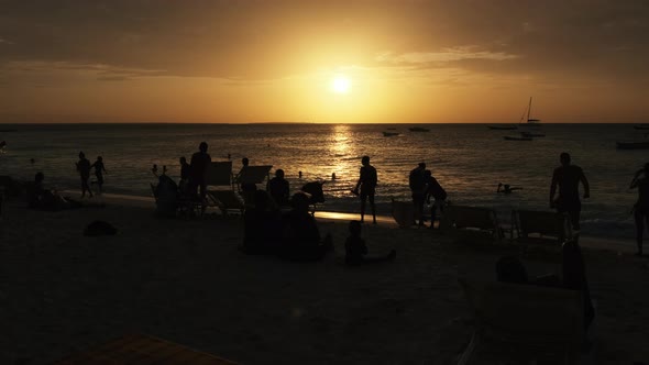 Silhouettes of People at Sunset Having a Rest By Ocean on the Beach Zanzibar alt