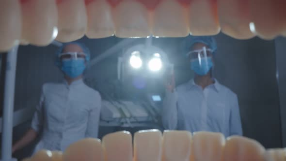 Macro Shot of Patient Opening Mouth and Dentist with Assistant Adjusting Lamp alt