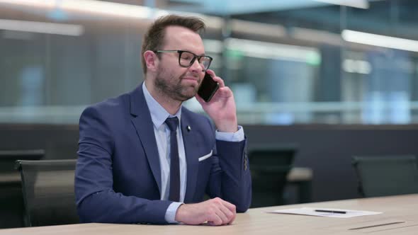 Middle Aged Businessman Talking on Phone at Work alt