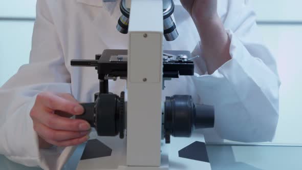 Female scientist looks into microscope alt