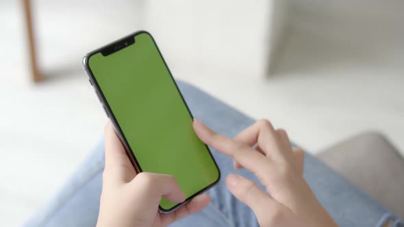 Asian woman holding hand and watching using smart phone with green screen.