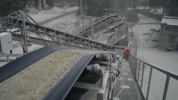 Male Employee Walking Near Conveyor Belt with Stone Rubble alt