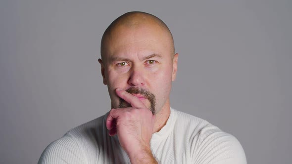 Portrait of a Bald Middle Aged Man with a Beard Who Thinks and Then Makes a Decision and Laughs alt