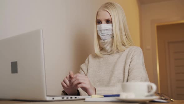 Businesswoman Working on a Laptop in a Cafe in a Medical Mask Removes alt