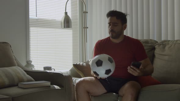 Slow Motion of Soccer Fan Kissing a Soccer Ball and Holding Mobile Phone alt