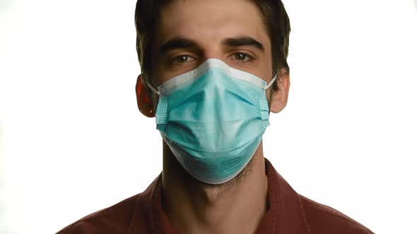 Portrait of a Young Man Taking Off His Medical Mask and Smiling on a White Background, Isolate