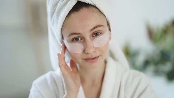 Portrait of a Woman at Home in a Bathrobe and Towel and Patches Under the Eyes alt