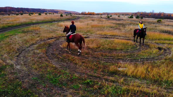 Two Beautiful Horses with Equestrians Are Going in Circle on the Field alt