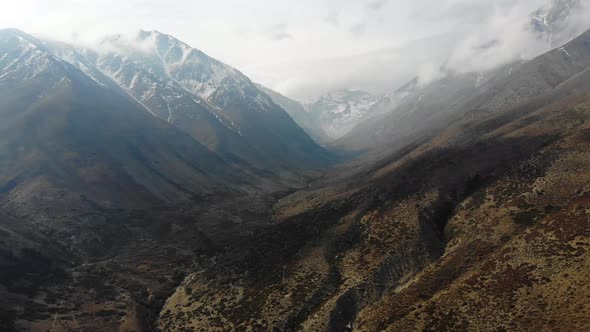 Aerial drone shot closing on snowy mountains on a cloudy day in Cordillera de los Andes-4K alt