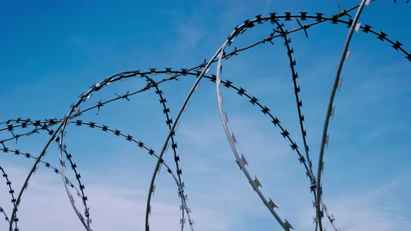 The Fence with Barbed Wire on the Background of a Gloomy Cloudy Dark Blue Sky alt