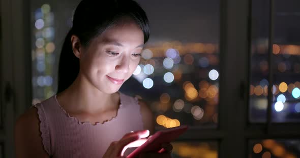 Woman work on mobile phone at home in the evening alt