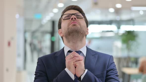 Portrait of Hopeful Young Businessman Praying Forgiveness alt