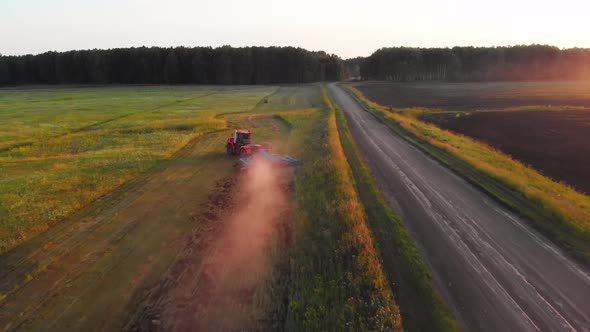 Red tractor with plow goes around obstacles alt