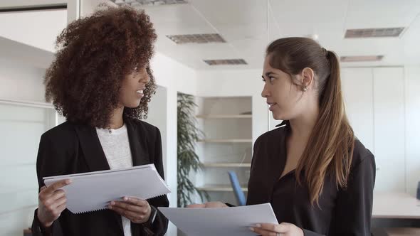 Female Business Colleagues Holding and Discussing Paper alt