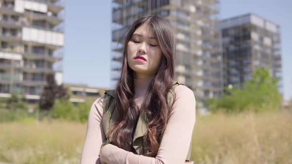 Young Asian Woman Acts Upset  Apartment Building Complex Blurry Background alt