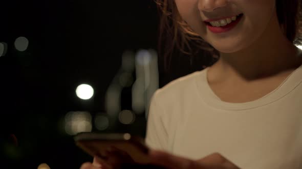 Asian tourist blogger woman using touchscreen technology at smartphone while walking on the street. alt