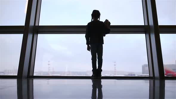 Little Girl in Airport Near Big Window While Wait for Boarding