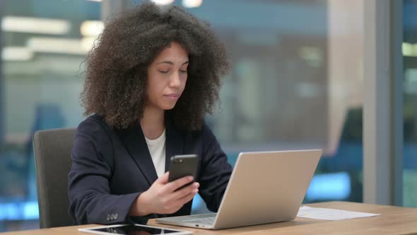 African Businesswoman with Laptop Using Smartphone alt