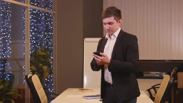 A Man in a Suit Uses a Phone in the Office