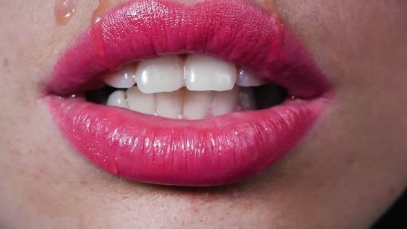 Female Beautiful Lips and White Teeth. Water Drops Run Down Her Lips, the Woman Licks the Drops From