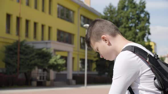 A Caucasian Teenage Boy Looks Around and Thinks About Something  Closeup  a School