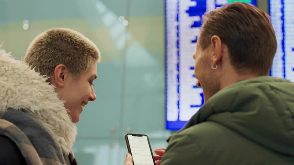 Young Couple Looking at Flight Schedule at Airport