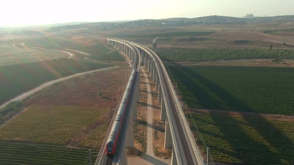 Train passing trough the tall bridges in the Judea valleys of Israel, aerial drone view alt