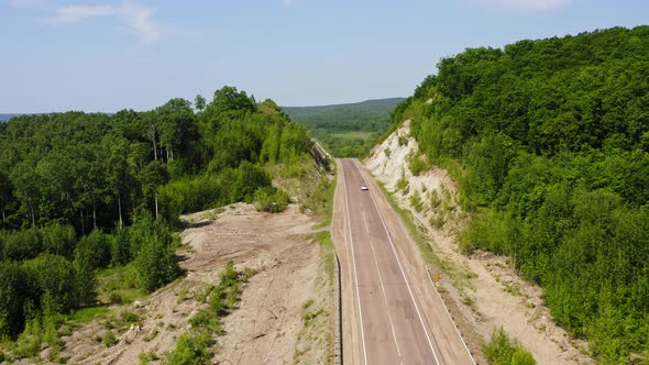 aerial-view-of-a-white-car-driving-along-a-country-road-by-mikedrone