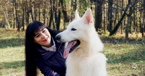 Happy Female Cheerfully Playing and Sitting with Dog in the Autumn Park. Love and Friendship with