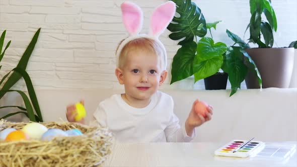 Funny happy child boy with easter eggs and bunny ears dancing