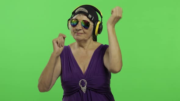 Elderly Woman Listens To Music in Headphones and Dances. Grandmother. Chroma Key alt
