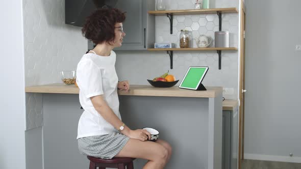 Woman Blogger Sitting in Kitchen and Record Video Blog on Digital Tablet