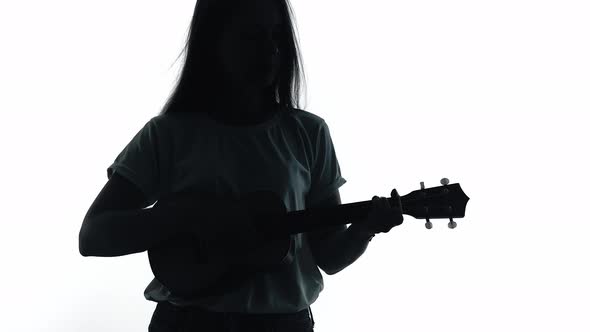 Silhouette of Girl Playing Ukulele in a White Studio