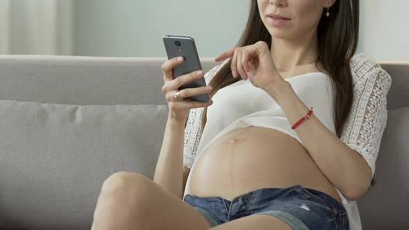 Future Mother Scrolling Cellphone Screen, Reading Pregnancy Blog, Online Advice alt