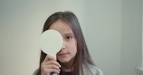 Schoolgirl Girl with a White Sign Closes Her Eye in the Ophthalmologist's Office alt