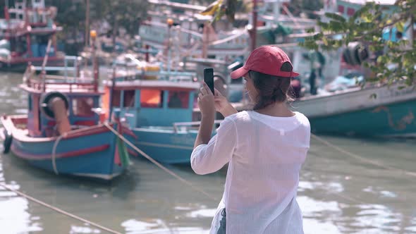 Girl with Phone in Pictorial Bay with Fishing Boats on Day alt