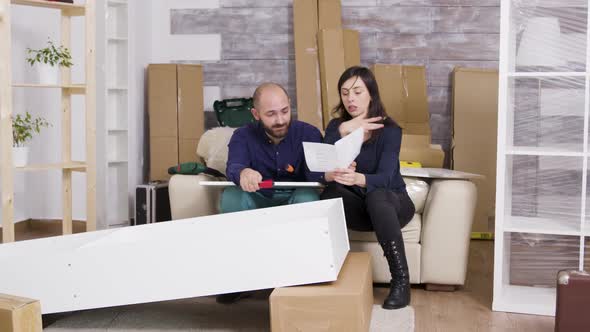 Caucasian Couple Arguing While Assembling a Shelf alt