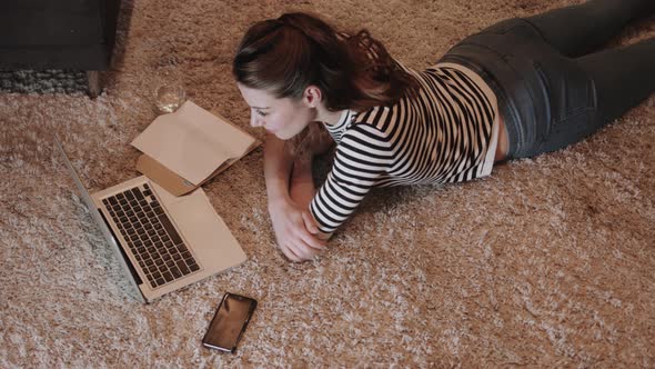 Young adult woman on floor working on laptop