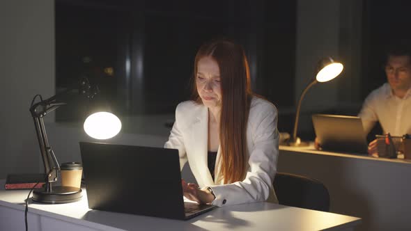 Young Business Woman Works at a Computer at Night